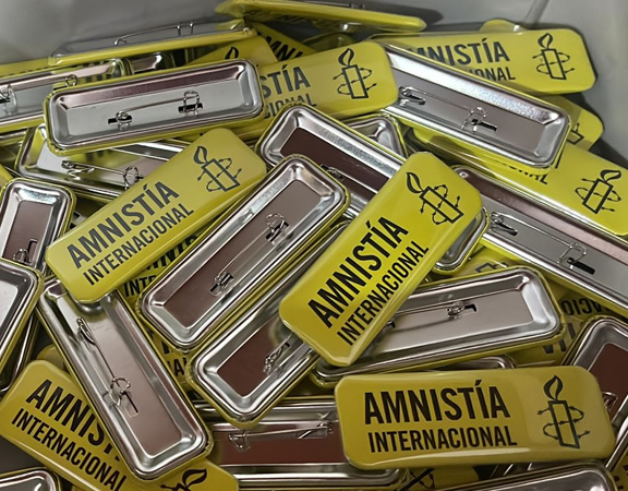 varias chapitas rectangulares para amnistia internacional con fondo amarillo